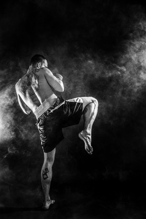 muscular kickbox or muay thai fighter punching in smoke